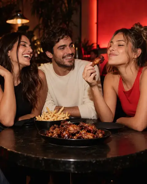 Escena de campaña: tres amigos comparten alitas en una mesa